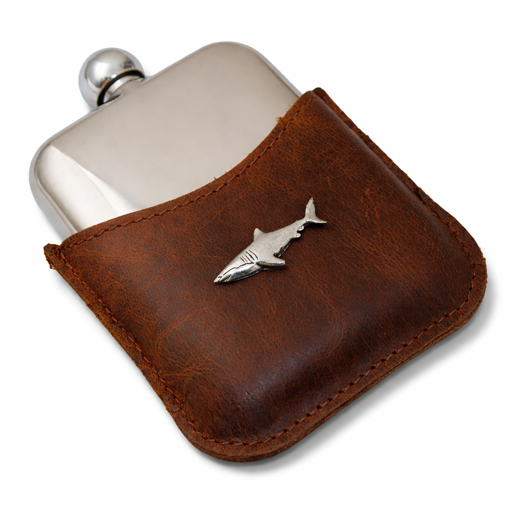 Silver flask with brown leather cover featuring a shark emblem on a white background